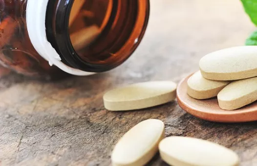 Pills spilled on a table with pill bottle in background
